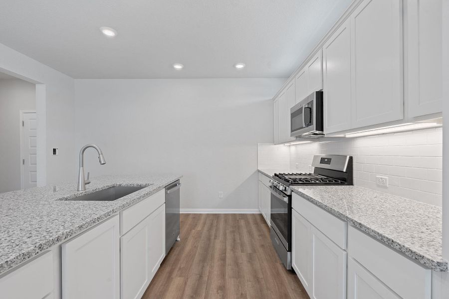 Kitchen featuring appliances with stainless steel finishes, light wood-type flooring, white cabinetry, tasteful backsplash, and recessed lighting Kitchen featuring appliances with stainless steel finishes, light wood-type flooring, white cabinetry, tasteful backsplash, and recessed lighting