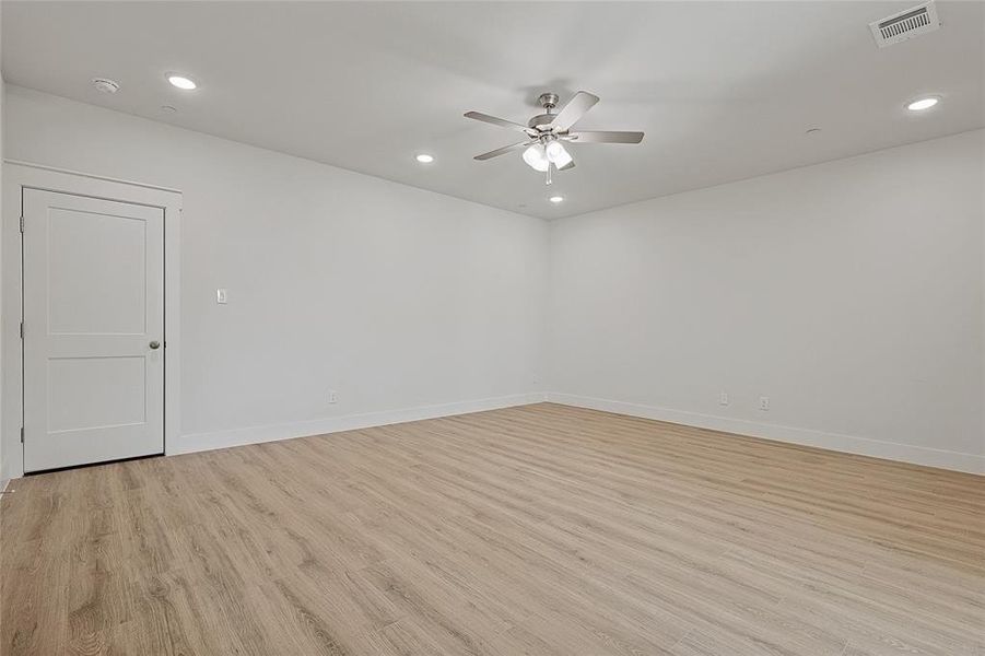 Spacious room featuring light-toned flooring, crisp white walls, and recessed lighting