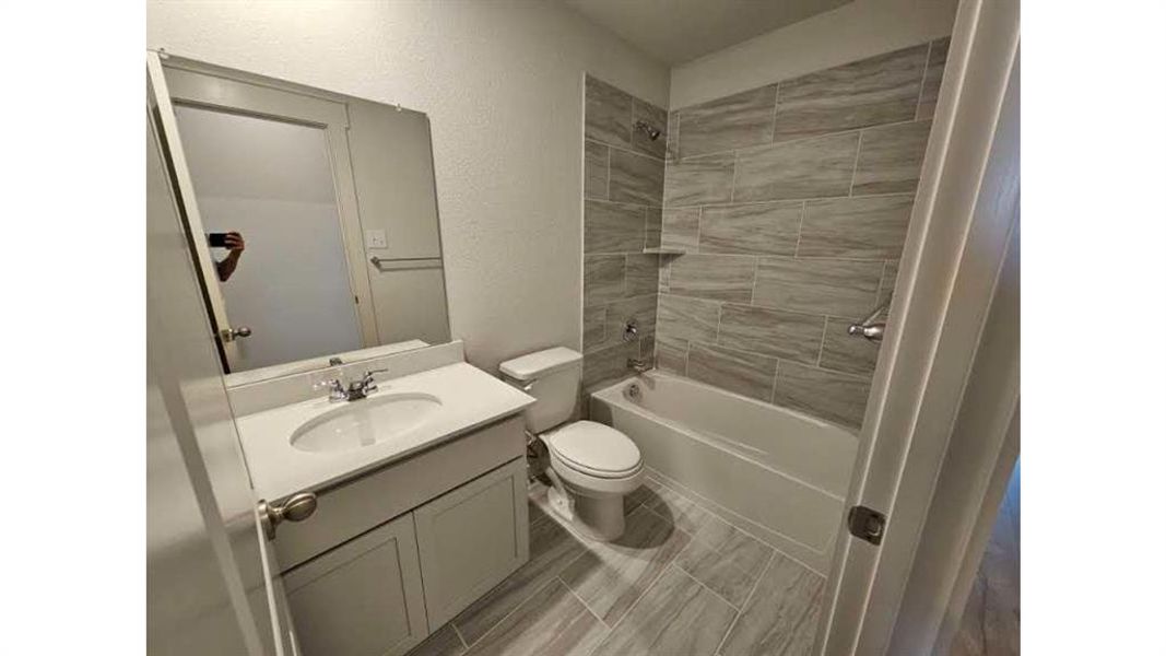 Modern bathroom featuring a white vanity with an integrated sink, a large wall-mounted mirror, and a toilet