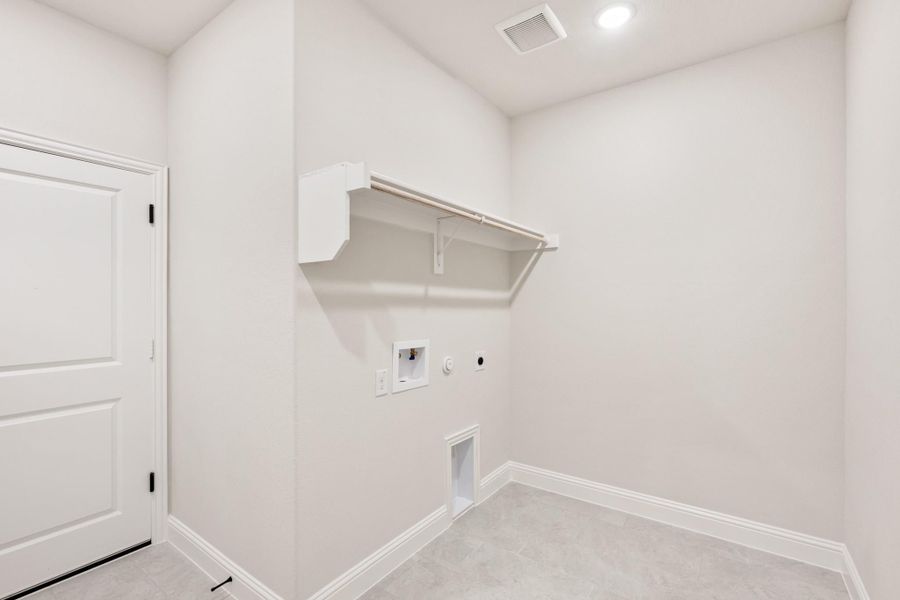 Empty laundry room with white walls, wall-mounted shelf, washer hookups, and recessed lighting Empty laundry room with white walls, wall-mounted shelf, washer hookups, and recessed lighting