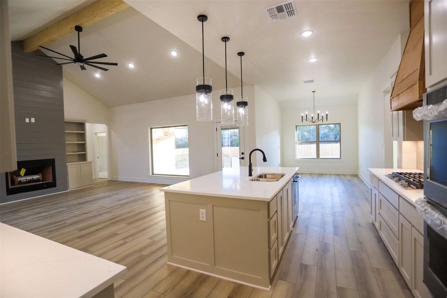 Kitchen with open floor plan, a fireplace, a center island with sink, and light wood-type flooring