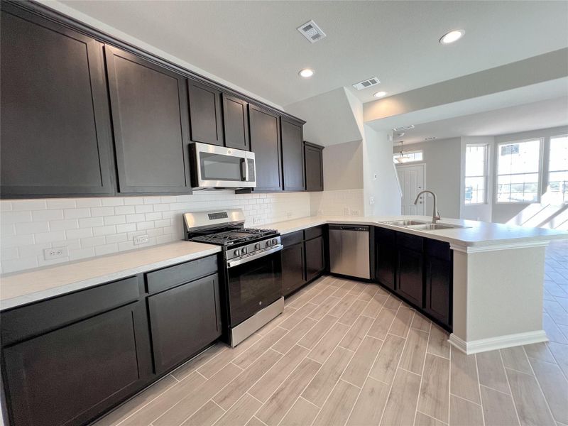 Kitchen featuring a sink, appliances with stainless steel finishes, a peninsula, and visible vents Kitchen featuring a sink, appliances with stainless steel finishes, a peninsula, and visible vents