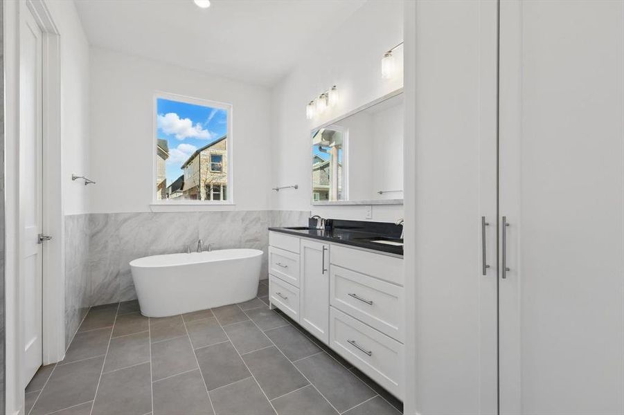 Full bathroom with a wainscoted wall, vanity, a freestanding bath, and tile patterned floors