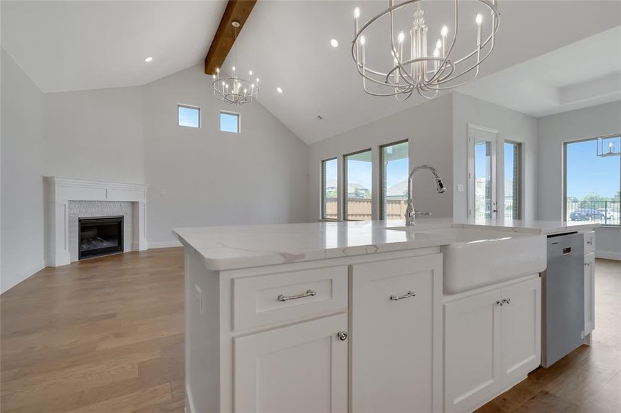 Kitchen featuring hanging light fixtures, light hardwood / wood-style floors, dishwasher, beamed ceiling, and a center island with sink