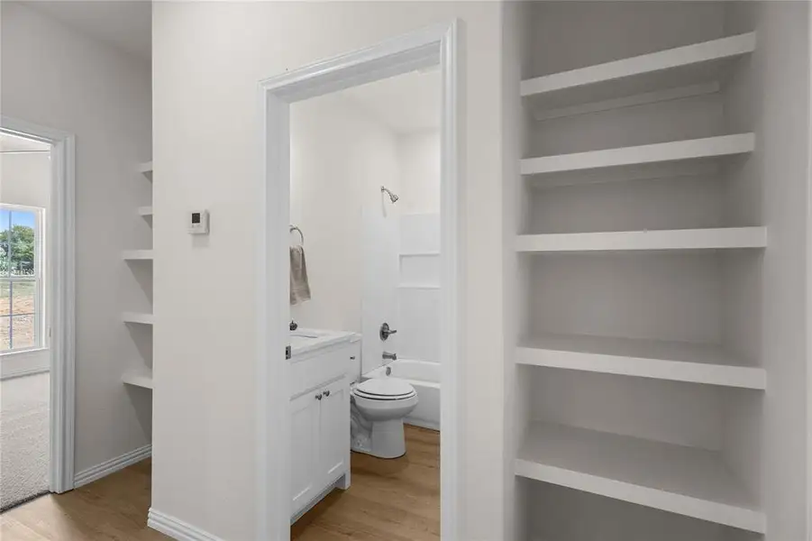 Bathroom featuring washtub / shower combination, light wood-style flooring, built in features, and vanity