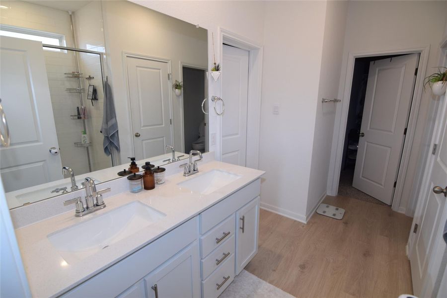 A spacious double vanity matches the light wood flooring and clean lines of this modern bath.
