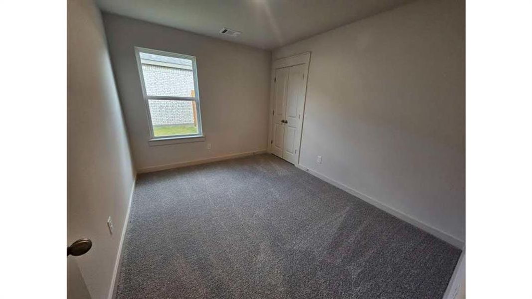 Carpeted room featuring a single window and a double-door closet