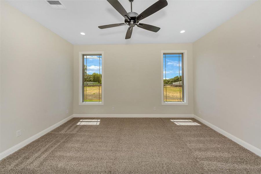 Carpeted spare room with plenty of natural light and ceiling fan