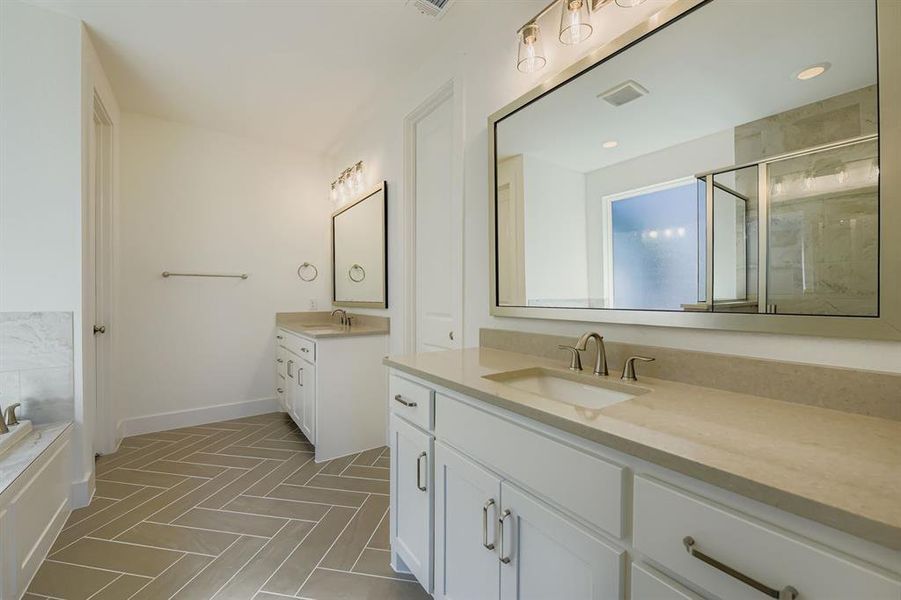 Full bathroom with two vanities, a marble finish shower, and a bath