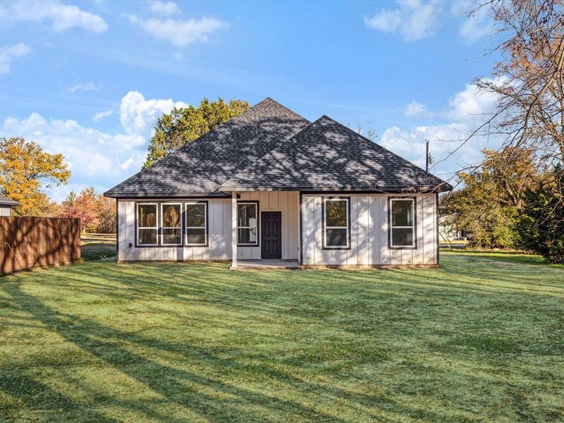 Back of property with a shingled roof, a patio, and board and batten siding