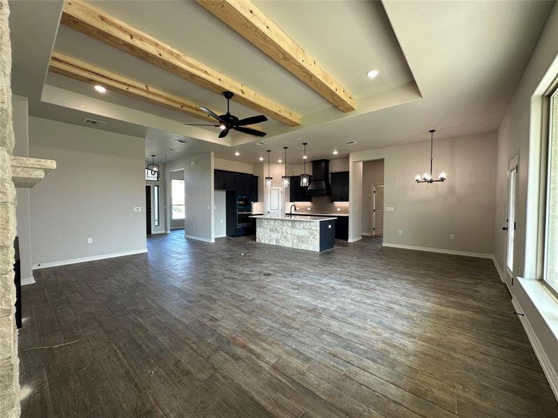 Unfurnished living room with beam ceiling, a chandelier, recessed lighting, ceiling fan, and dark wood finished floors Unfurnished living room with beam ceiling, a chandelier, recessed lighting, ceiling fan, and dark wood finished floors
