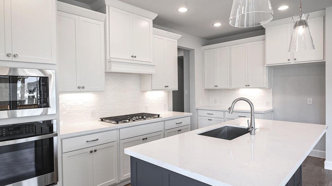 Kitchen featuring appliances with stainless steel finishes, decorative backsplash, white cabinets, an island with sink, and recessed lighting