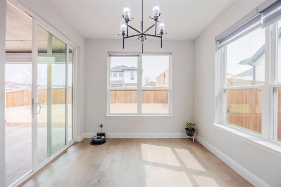 Unfurnished dining area featuring light wood finished floors, a notable chandelier, and baseboards