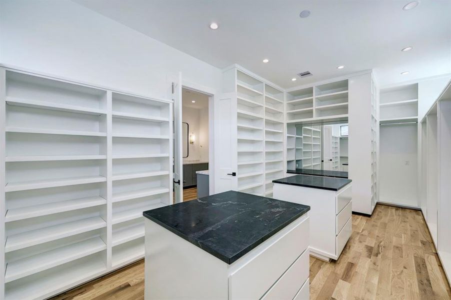 Massive primary closet with dressing table and dual packing islands