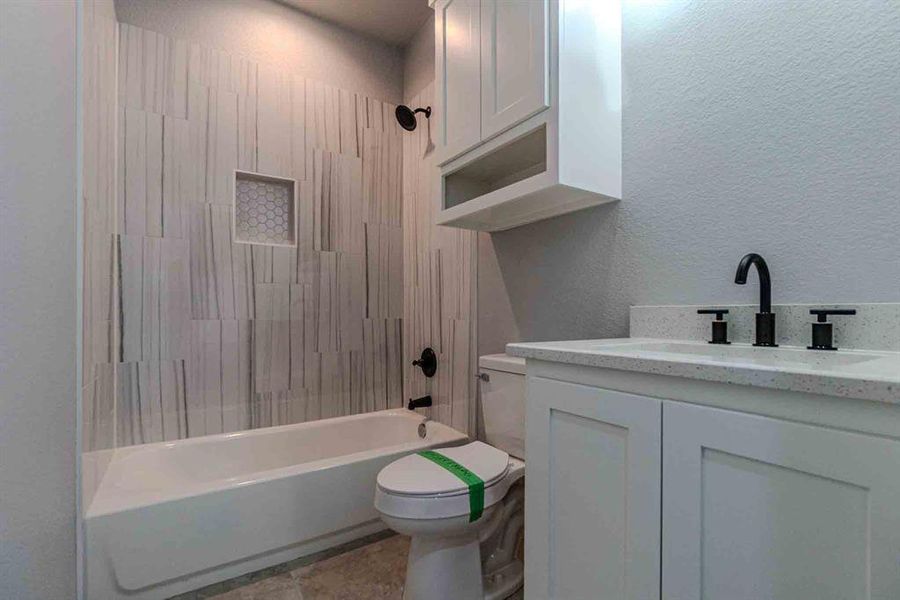 Full bath with a textured wall, vanity, and shower / bath combination Full bath with a textured wall, vanity, and shower / bath combination