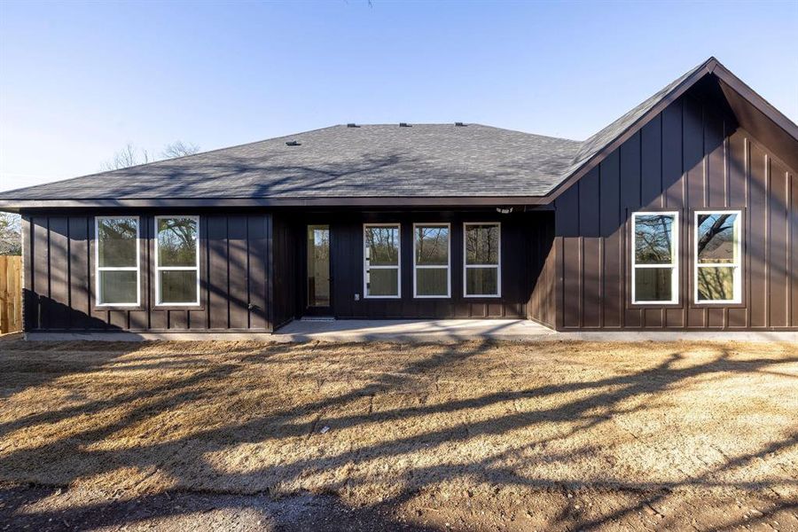 Back of house featuring board and batten siding and roof with shingles