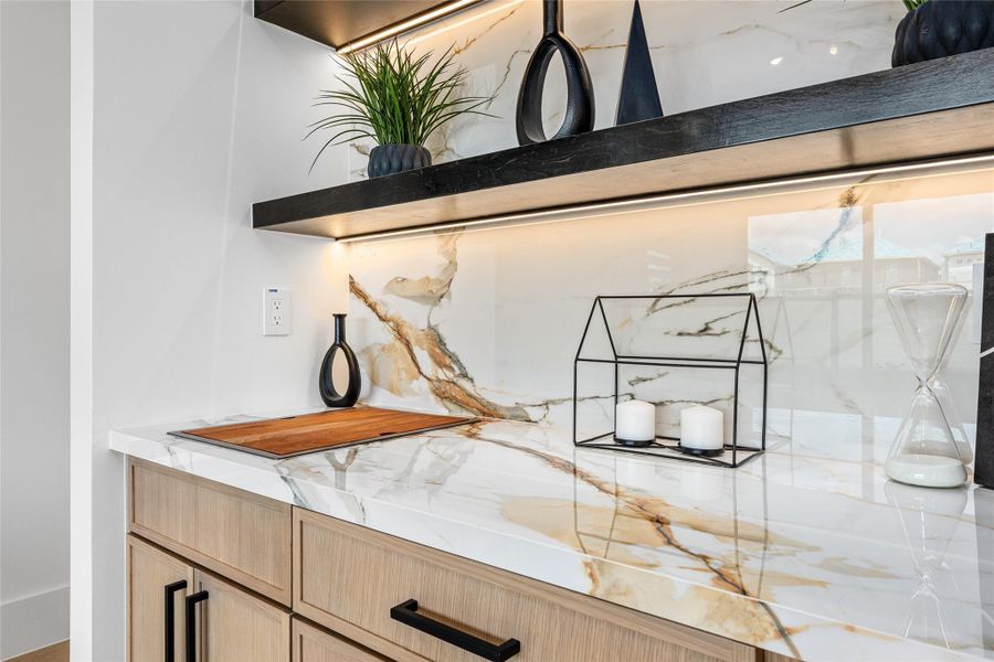 Thoughtfully placed wet bar offers the ideal setting for gatherings—enhanced by sleek cabinetry, hidden faucet, and wooden cover board for seamless presentation