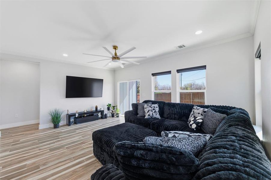 Living room with recessed lighting, wood finished floors, crown molding, and a ceiling fan