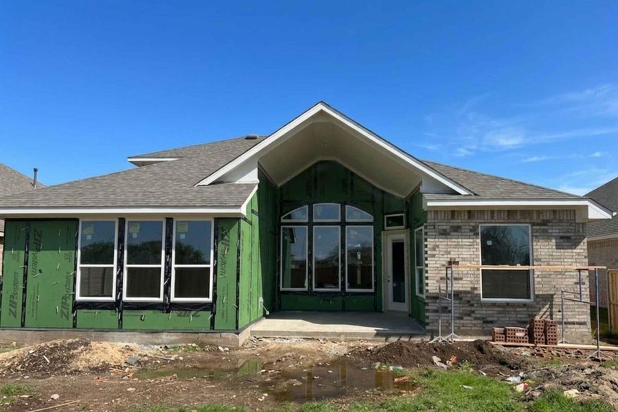 Rear view of house with brick siding, roof with shingles, and a patio