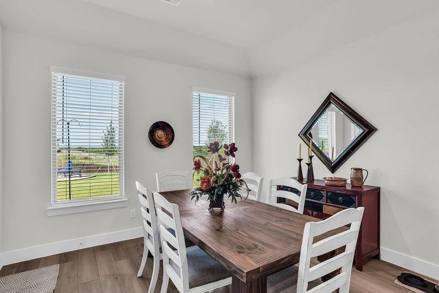 Dining/Breakfast room featuring wood-finish flooring, white walls, and backyard views opens to Kitchen and Living rooms