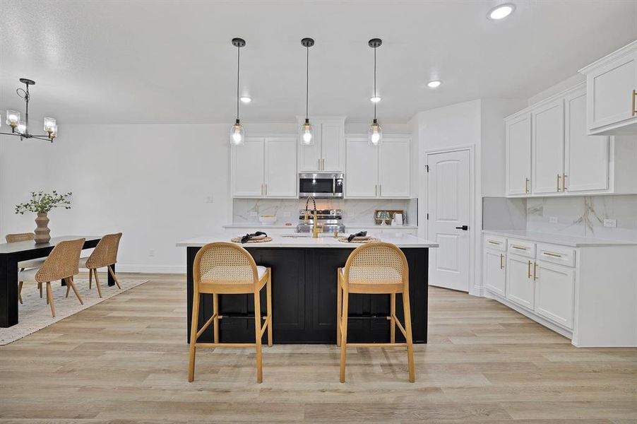 Kitchen with pendant lighting, light hardwood / wood-style flooring, white cabinetry, and tasteful backsplash