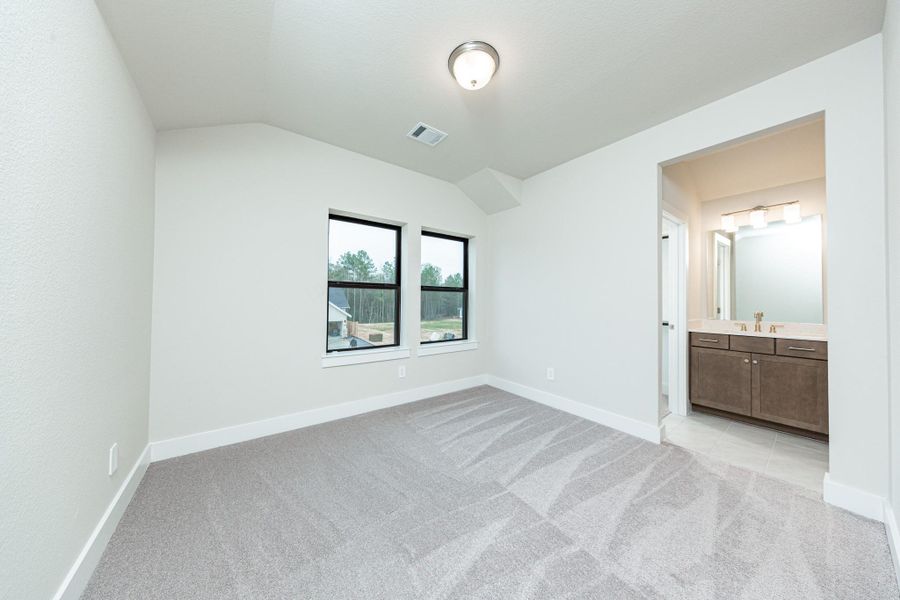 This inviting secondary bedroom boasts of two large windows, plush carpeting, a neutral color palette, and easy access to the secondary bathroom.