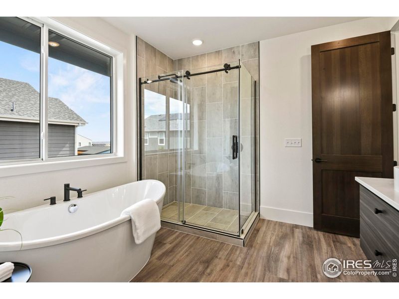 Large shower with floor to ceiling tile and stand alone soaking tub.