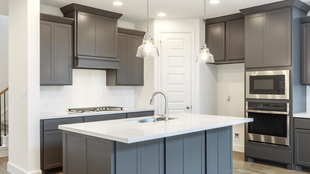 Kitchen with a sink, decorative backsplash, wood finished floors, and stainless steel appliances Kitchen with a sink, decorative backsplash, wood finished floors, and stainless steel appliances