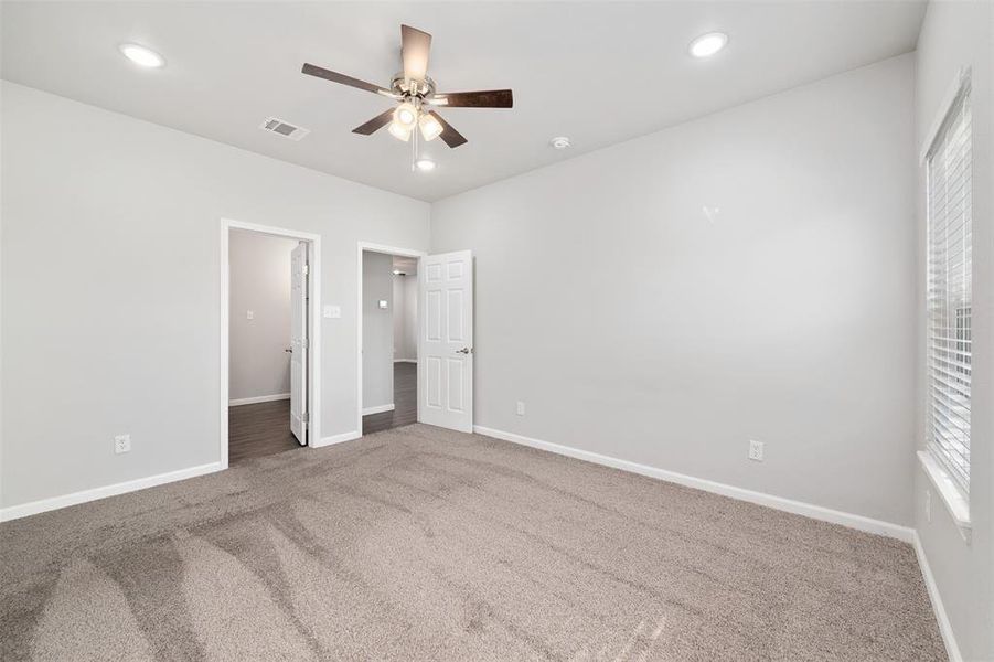 Carpeted bedroom with ceiling fan, a spacious closet, and a closet