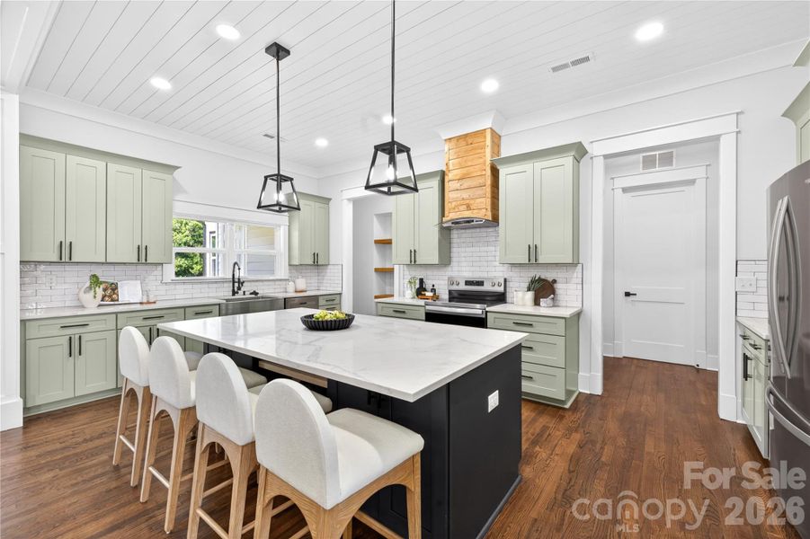 From the ceiling details to the soft cabinet color, warm wood hood, oversized island, and wide plank floors… every finish in this kitchen was picked to make the space feel custom and inviting