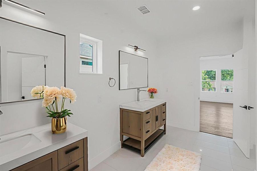 Full bathroom featuring two vanities, recessed lighting, and tile patterned flooring