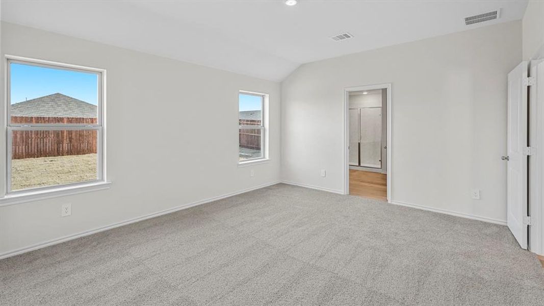Unfurnished bedroom with vaulted ceiling, light colored carpet, recessed lighting, and connected bathroom