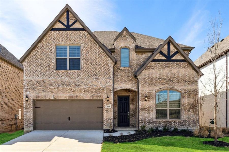 Tudor home with a front yard and a garage