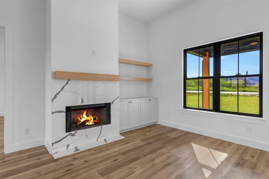 Living room with a high end fireplace wrapped in quartz and light wood-style floors