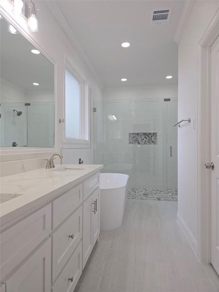 Bathroom with double vanity, a stall shower, a soaking tub, crown molding, and light tile patterned floors Bathroom with double vanity, a stall shower, a soaking tub, crown molding, and light tile patterned floors