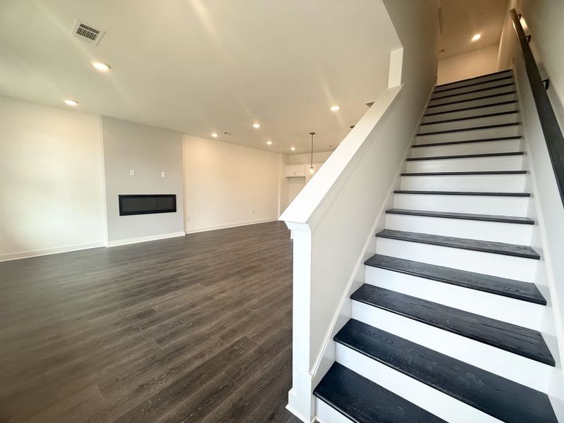 Stairs featuring recessed lighting, wood finished floors, and a large fireplace
