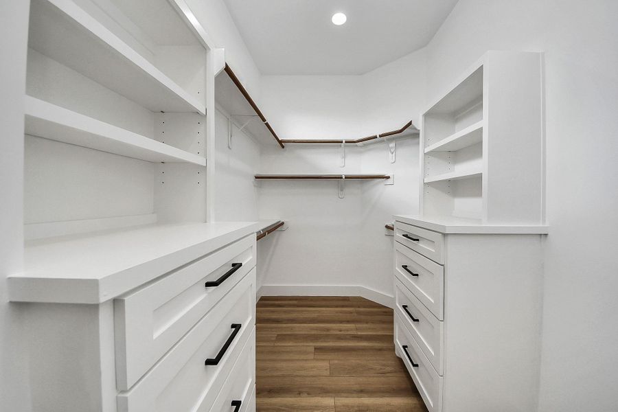 Spacious primary walk-in closet featuring custom built-in shelving and drawers, offering plenty of room for organized storage. Thoughtfully designed layout provides both functionality and ease for everyday living.