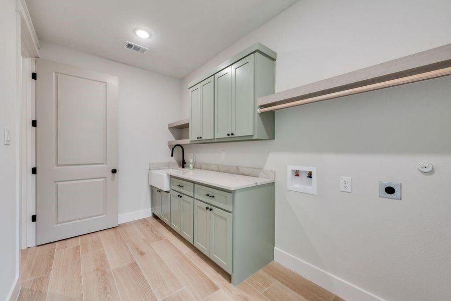 Washroom with light wood-type flooring, sink, hookup for a washing machine, and hookup for an electric dryer