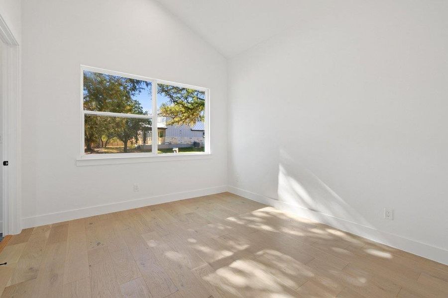 Spare room featuring light wood-style flooring and high vaulted ceiling