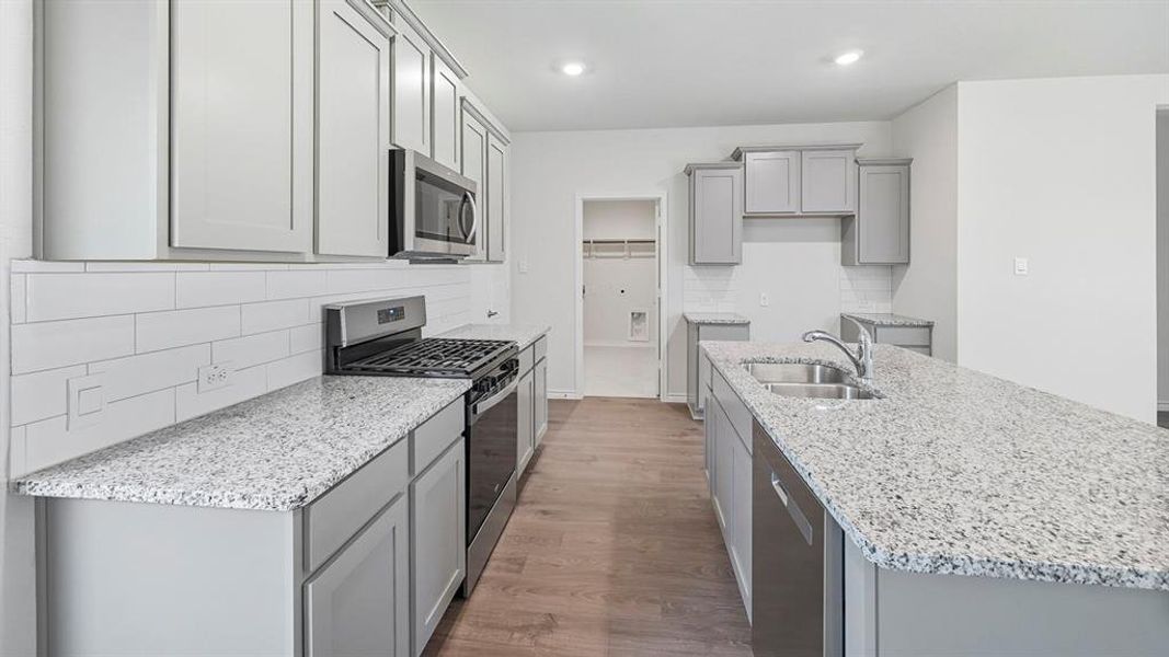 Kitchen featuring gray cabinets, stainless steel appliances, light stone countertops, dark wood finished floors, and recessed lighting