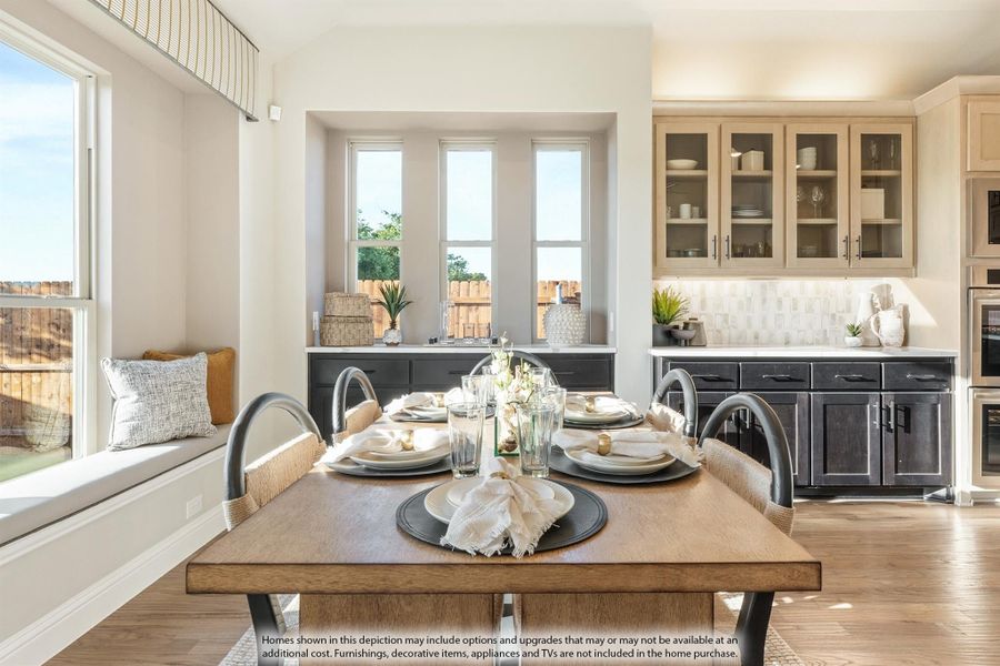 Dining area with wood table set for four, adjacent to kitchen with dark cabinets and window seat Dining area with wood table set for four, adjacent to kitchen with dark cabinets and window seat
