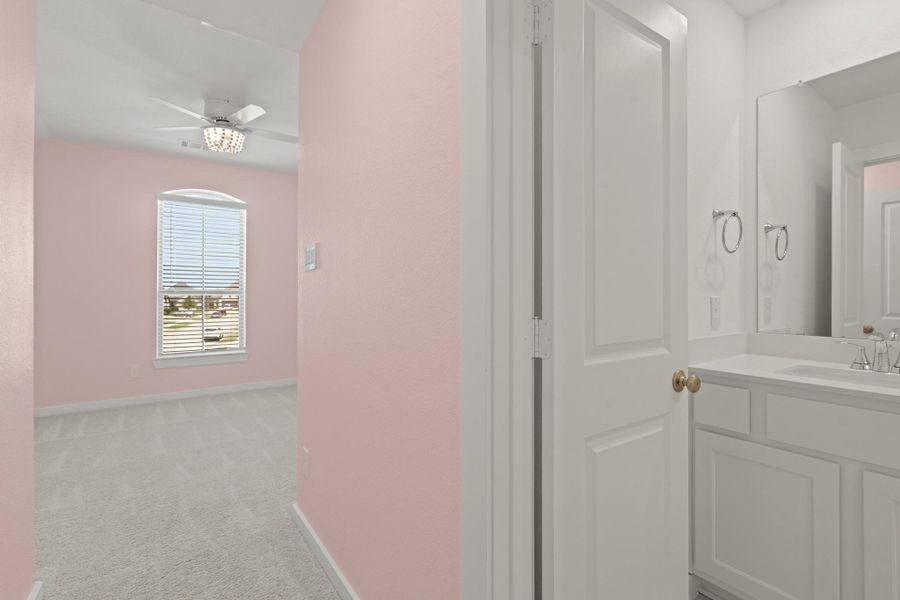 Bright and inviting, this secondary bedroom offers bright natural light, plush carpet, ceiling fan, and private bathroom making it the perfect retreat for family or guests.