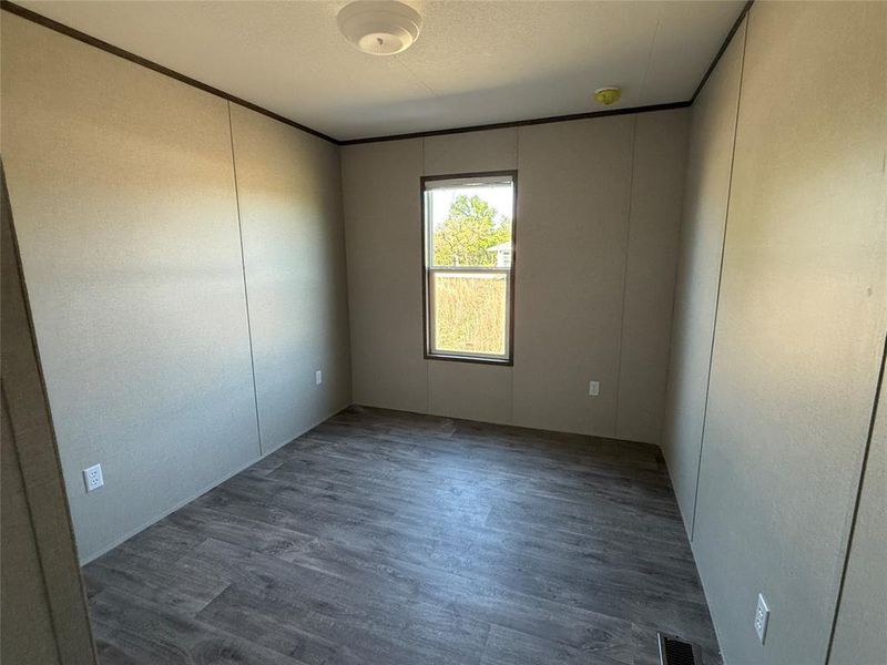 Empty room featuring visible vents, ornamental molding, and wood finished floors