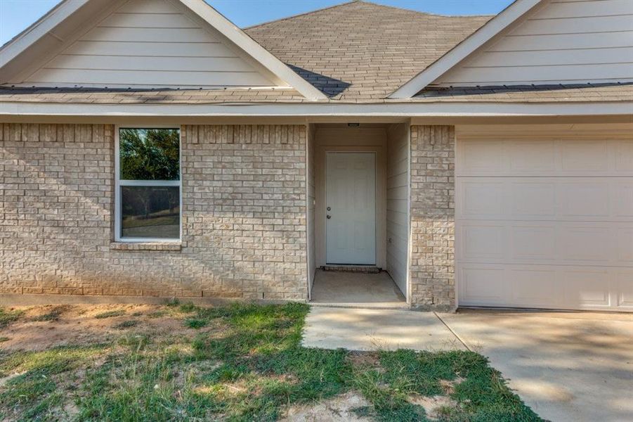 Entrance to property featuring a garage and brick siding