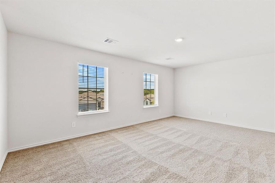 Spacious room featuring neutral carpet flooring, two windows with horizontal blinds, and recessed lighting