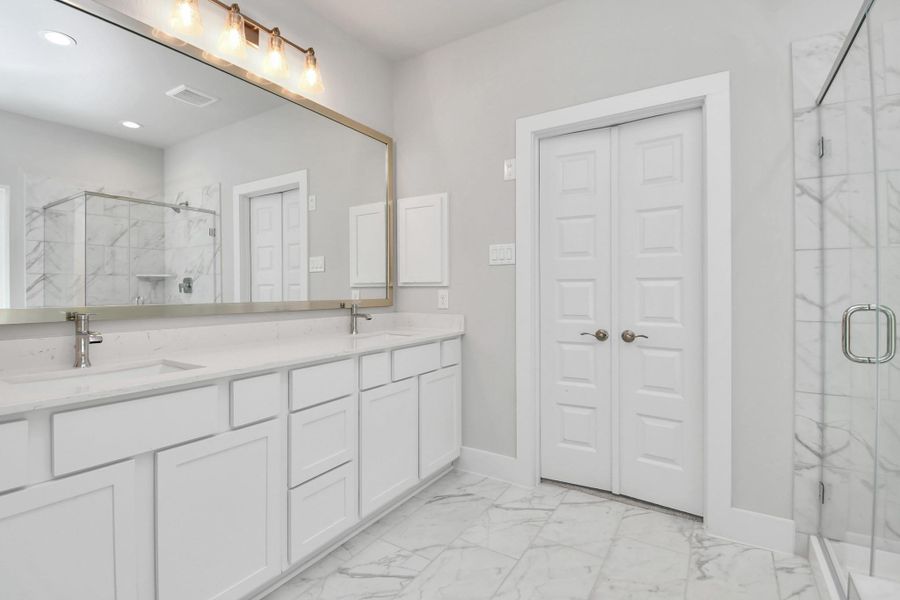 Elevate your daily routine at the elegant vanity, now equipped with double sinks, light countertops, modern hardware, and beautiful vanity lights. Sample photo of completed home with similar floor plan. Actual colors and selections may vary. Elevate your daily routine at the elegant vanity, now equipped with double sinks, light countertops, modern hardware, and beautiful vanity lights. Sample photo of completed home with similar floor plan. Actual colors and selections may vary.