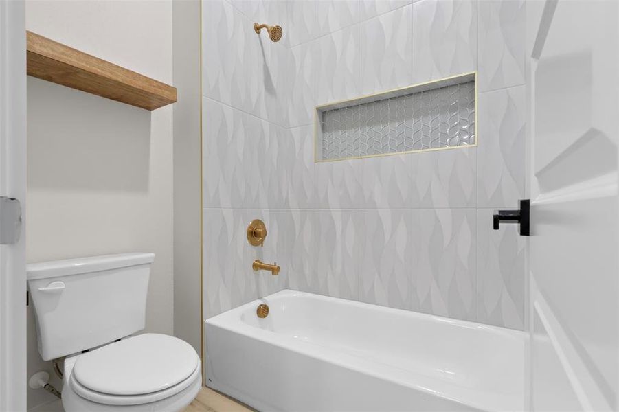 Bathroom featuring tiled shower / bath combo and toilet