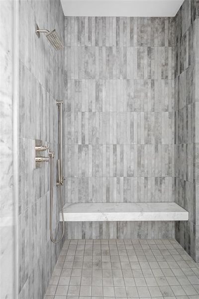 The luxurious Shadow Storm honed marble bench and surround of the sleek primary walk-in shower are beautifully complemented by polished nickel hardware and vertical shower tiles.