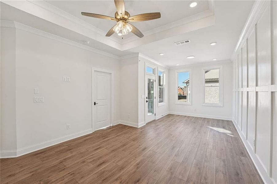 Primary bedroom with a tray ceiling, ornamental molding, recessed lighting, wood finished floors, and ceiling fan. Image is of a previously built Chamberlain plan.