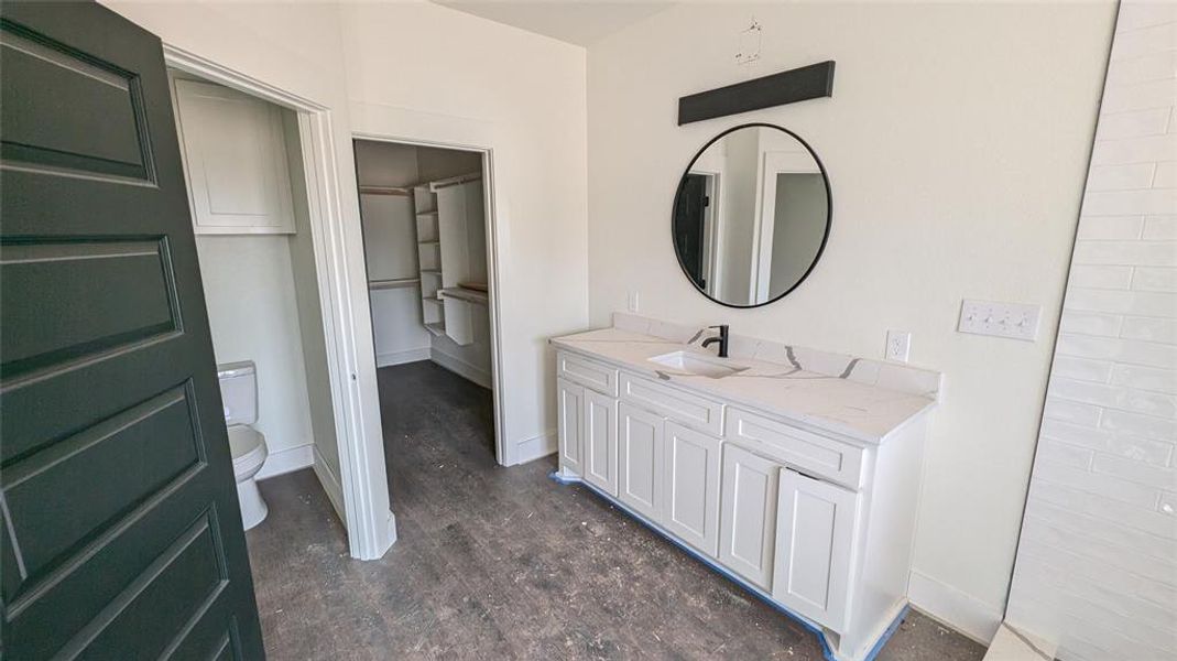 Full bath with vanity, toilet, wood finished floors, and baseboards